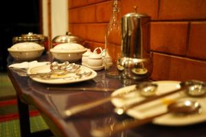 a table with plates and spoons on it at Ambar Villa in Chikmagalūr