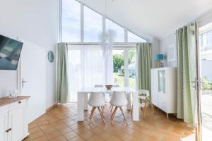 a white dining room with a white table and chairs at Ferienhaus Meerblick in Wohlenberg