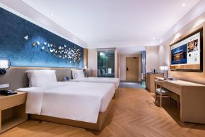 une chambre avec un grand lit blanc et un bureau dans l'établissement 青岛崂山石老人会展中心桔子水晶酒店, à Qingdao