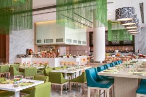 a restaurant with white tables and green chairs at Downtown Rotana in Manama