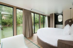 1 dormitorio con 2 camas y ventanas grandes en L'Escale Royale Poissy Île de Migneaux - Seine, en Poissy