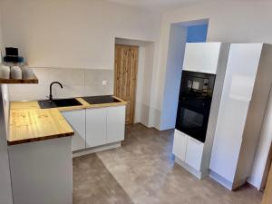a kitchen with white cabinets and a black appliance at Rybka living apartments in Přerov