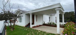 a white house with columns and flowers in the yard at Willostays Snowmanor kodaikanal in Kodaikānāl