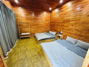 two beds in a room with wooden walls at Amy Homestay Mộc Châu in Bản Àng +16 photos