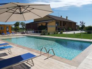 a swimming pool with an umbrella and a house at Cascina Olmetto di Sotto in Ghedi
