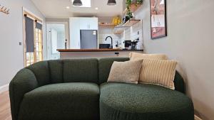 a green couch in a living room with a kitchen at Prospect Cottage Ballarat in Ballarat +10 photos