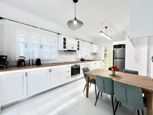 STAY Cavo Bay Villa في بروتاراس: مطبخ بخزائن بيضاء وطاولة خشبية