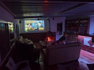 a man sitting on a couch in a living room with a television at 2 Wheels Granada Motocamp in Vallequemado