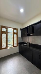 a kitchen with a black counter top and a window at The Kalath House in Vashisht