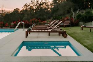 a row of benches sitting next to a swimming pool at Vila Coura in Amarante