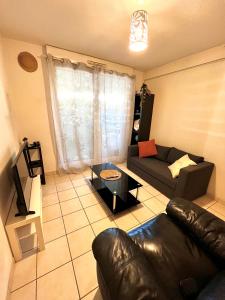 a living room with a leather couch and a table at Location courte durée T2 avec terrasse à Montpellier in Montpellier