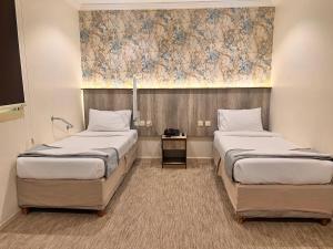 a room with two beds and a painting on the wall at Al-Kkulfaa Al-Faisaliah - فندق الخلفاء الفيصليه in Makkah