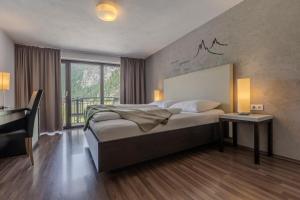 ein Schlafzimmer mit Bett, Schreibtisch und Fenster in der Unterkunft Hotel Bergwelt in Längenfeld