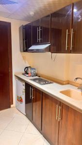a kitchen with wooden cabinets and a sink at Al-Kkulfaa Al-Faisaliah - فندق الخلفاء الفيصليه in Makkah