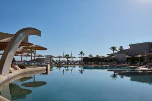 une piscine avec chaises et parasols dans un complexe hôtelier dans l'établissement Atlantica Kalliston Resort - Adults Only, à Stalós