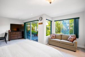 a bedroom with a bed and a couch and a tv at Garden Suite near Jericho Beach in Vancouver