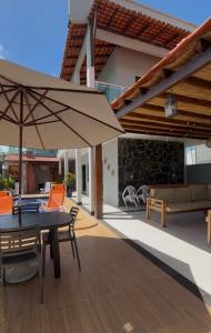 Un patio con una sombrilla y una mesa y sillas. en Casa Por Do Sol, en Salinópolis