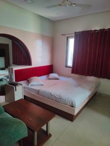 a bedroom with two beds with red curtains and a table at Hotel Paras in Udaipur