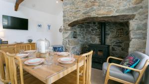 comedor con mesa de madera y chimenea de piedra en Fron Olau, en Nefyn