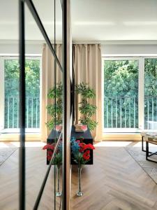 salon z 2 oknami i stołem z kwiatami w obiekcie Modern Apartment w Bielsku Białej