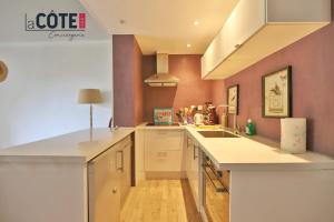 a large kitchen with white counters and pink walls at Melusine in Sausset-les-Pins +6 photos