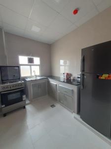 a large kitchen with a refrigerator and a sink at اجنحه اسوار للشقق الفندقيه in Salalah