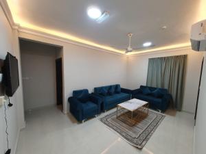 un soggiorno con divani blu e un tavolo di اجنحه اسوار للشقق الفندقيه a Salalah