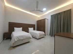 una camera da letto con due letti, un tavolo e un soffitto di اجنحه اسوار للشقق الفندقيه a Salalah