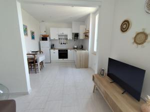 a kitchen and living room with a flat screen tv at Appartement cosy village entre mer et nature in Le Pradet