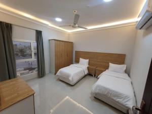 a bedroom with two beds and a ceiling fan at اجنحه اسوار للشقق الفندقيه in Salalah +40 photos