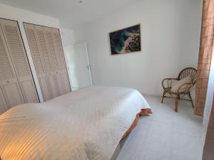 a white bedroom with a bed and a chair at Appartement cosy village entre mer et nature in Le Pradet
