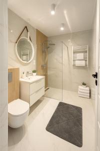Un baño con inodoro, lavabo y espejo. en BALTIQ Apartments, en Ustka