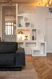 a living room with a black couch and white walls at Lille Centre - Grand Studio atypique ! in Mons-en-Baroeul