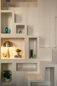 a white wall with shelves with plants and a lamp at Lille Centre - Grand Studio atypique ! in Mons-en-Baroeul