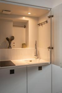 a white kitchen with a sink and a mirror at Lille Centre - Grand Studio atypique ! in Mons-en-Baroeul