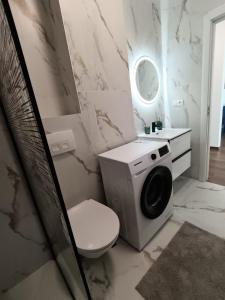 a bathroom with a toilet and a washing machine at B&B ApartHotel in Bistriţa