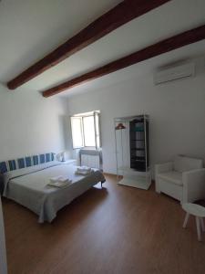 a white bedroom with a bed and a chair at Casa Rasi in Maratea