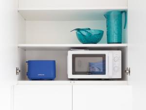 a white microwave sitting on top of a shelf at Sublime appartement face à la mer avec accès plage in Palavas-les-Flots
