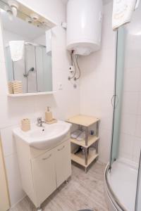Un baño blanco con lavabo y ducha. en Apartments Mihael, en Baška