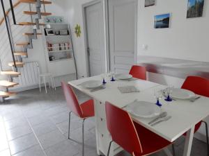 a dining room with a white table and red chairs at L 'esprit Loft in Montreuil-sur-Maine