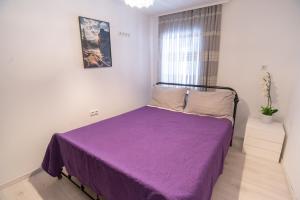 Un dormitorio pequeño con una cama morada con una ventana. en Apartments Mihael, en Baška