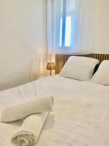 una camera da letto con due letti con lenzuola bianche e una finestra di Appartement climatisé côté port a Canet-en-Roussillon