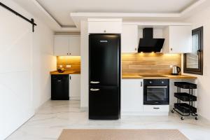 a kitchen with white cabinets and a black refrigerator at Sweet Home Turunc - Sea View Suites with One Bedroom in Turunç