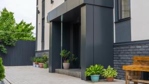 Un edificio negro con plantas en macetas en una acera. en SingKol Suites, en Bishkek