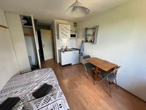 a bedroom with a bed and a table and a kitchen at Studio centre ville Paray-le-Monial in Paray-le-Monial