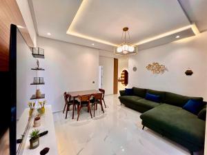 a living room with a green couch and a table at Bright Corniche Escape - 2 BR Urban Flat in Tangier