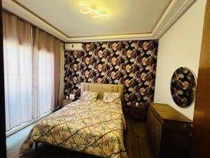 a bedroom with a bed with a floral accent wall at Appartement S1 Haut Standing Monastir in Monastir