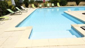 a large swimming pool with lounge chairs in a resort at La Galerie gîte climatisé 4 chambres 8 personnes, 2 salles d'eau, 2 WC, WIFI, parking, piscine chauffée à partager, animaux acceptés, Gîte en pleine nature in Lorignac