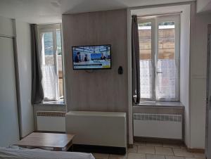 a room with a tv on a wall with windows at STUDIO 6 LUZ SAINT SAUVEUR 5 Pers in Luz-Saint-Sauveur