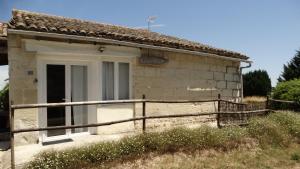 an old stone house with a white door and a fence at La Galerie gîte climatisé 4 chambres 8 personnes, 2 salles d'eau, 2 WC, WIFI, parking, piscine chauffée à partager, animaux acceptés, Gîte en pleine nature in Lorignac +20 photos